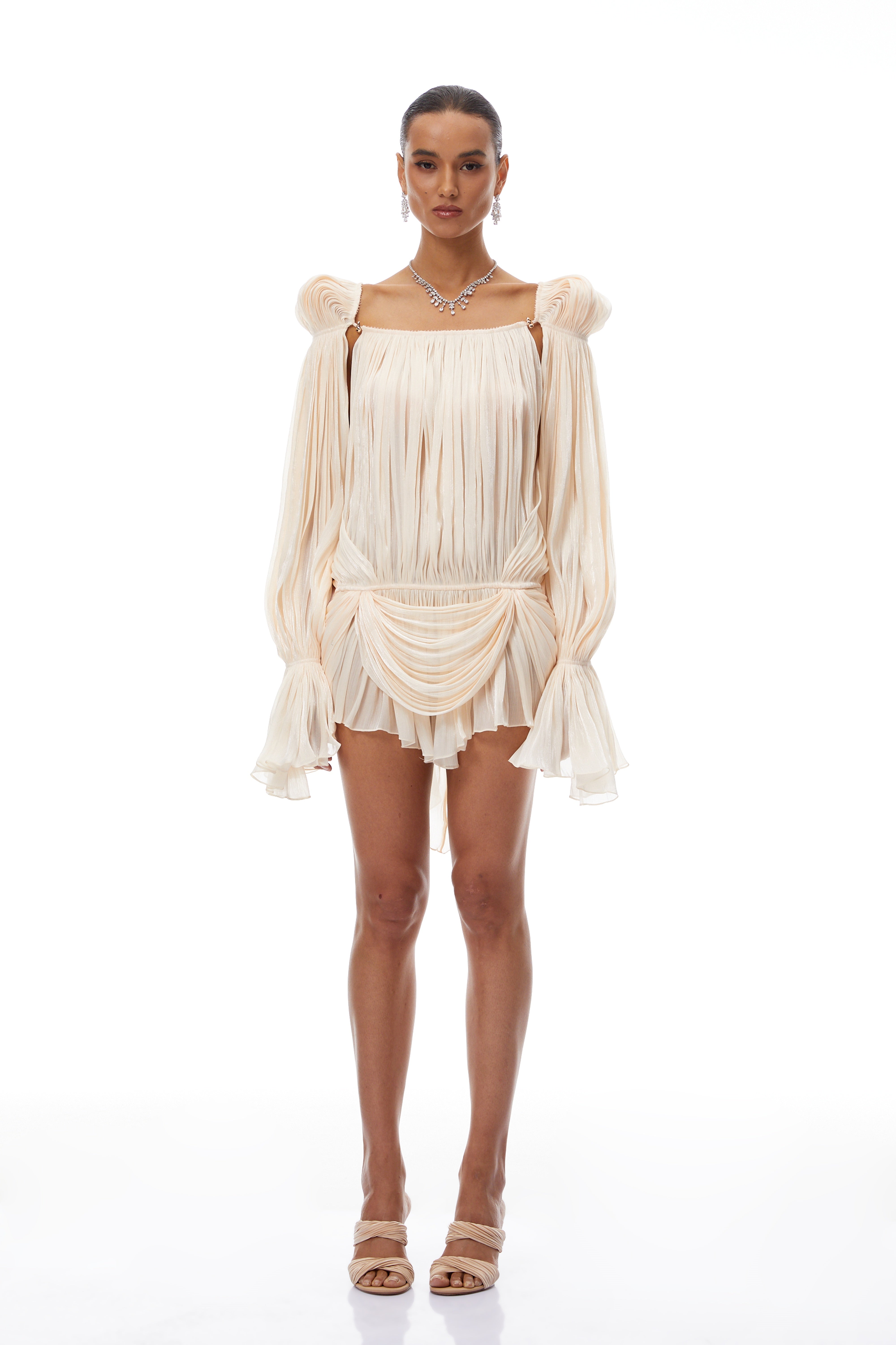 Cream plissé mini dress with a square neckline, structured puff sleeves, and a draped ruffled skirt