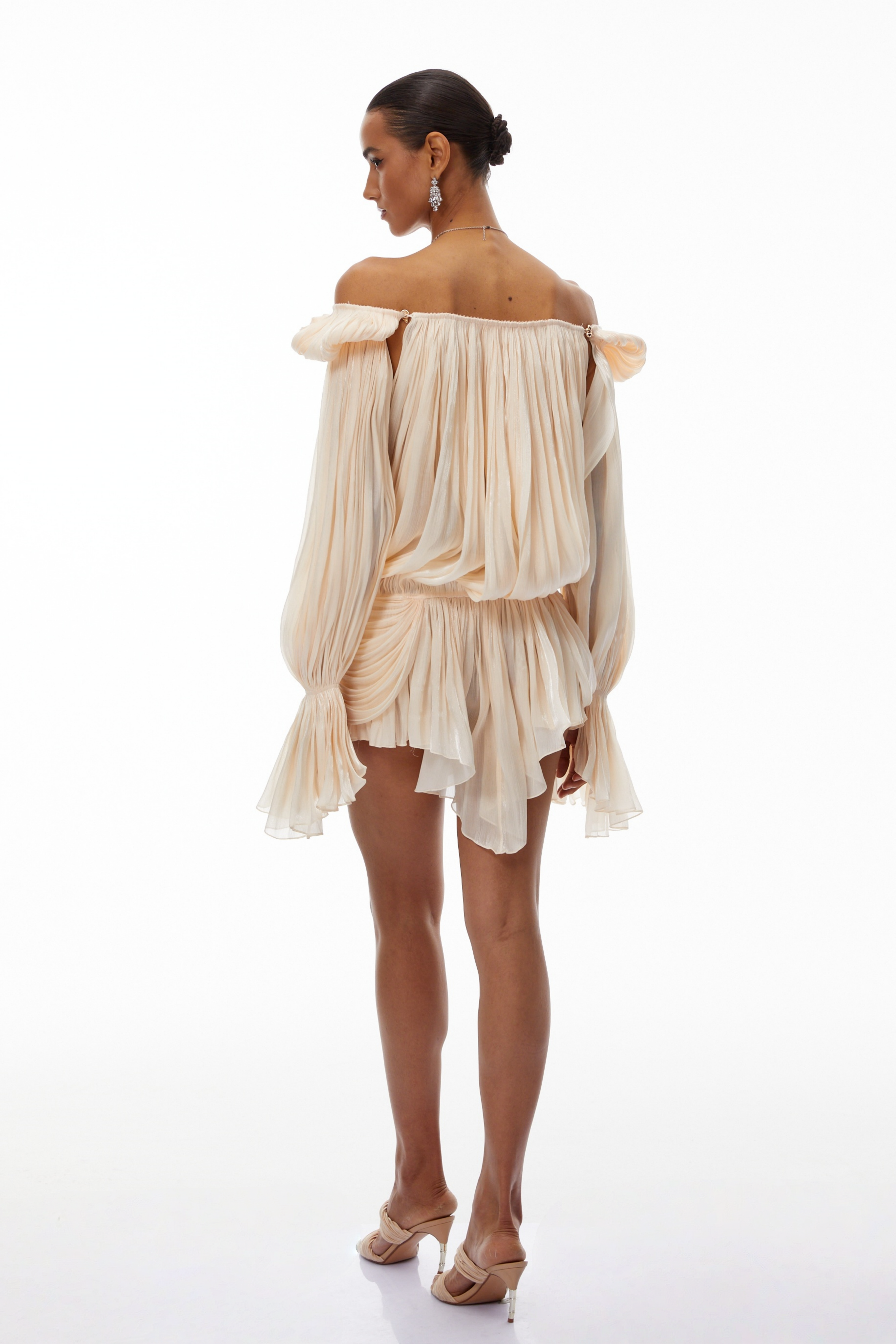 Cream plissé mini dress with a square neckline, structured puff sleeves, and a draped ruffled skirt