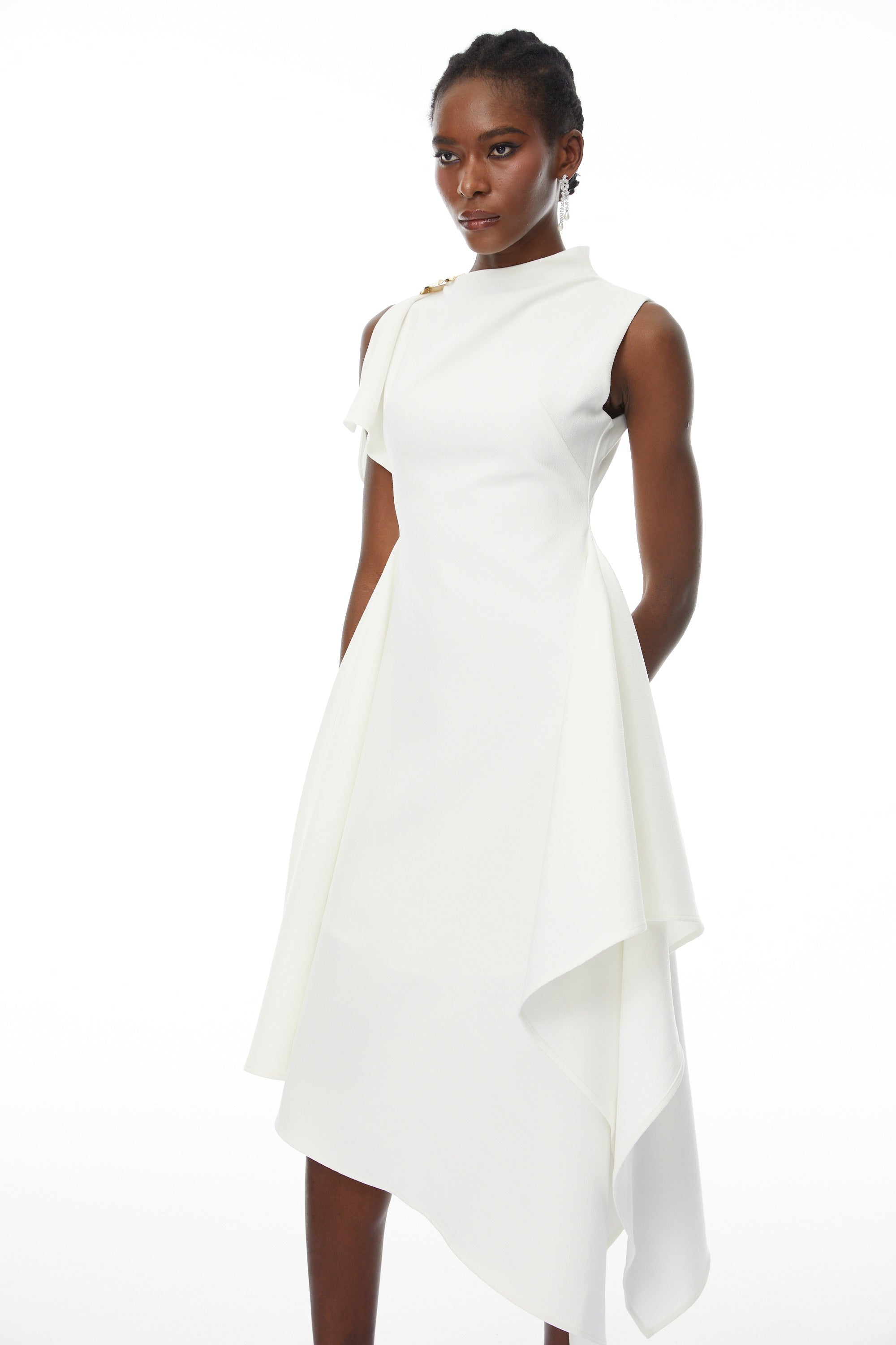 White sleeveless midi dress featuring a high drape neck with a brooch detail and a structured asymmetric handkerchief skirt