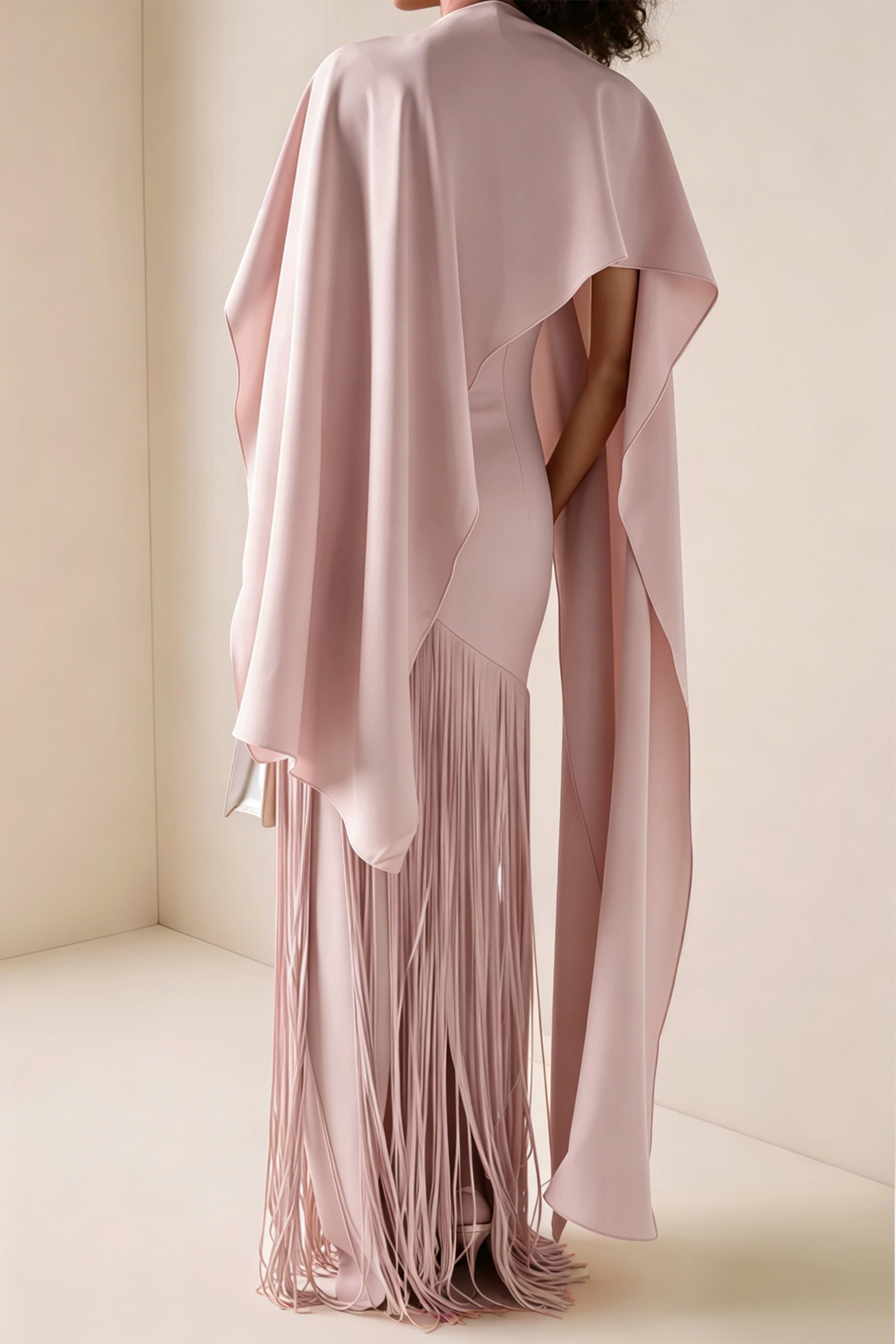 Light pink cape maxi dress with an asymmetrical waist and long fringe skirt