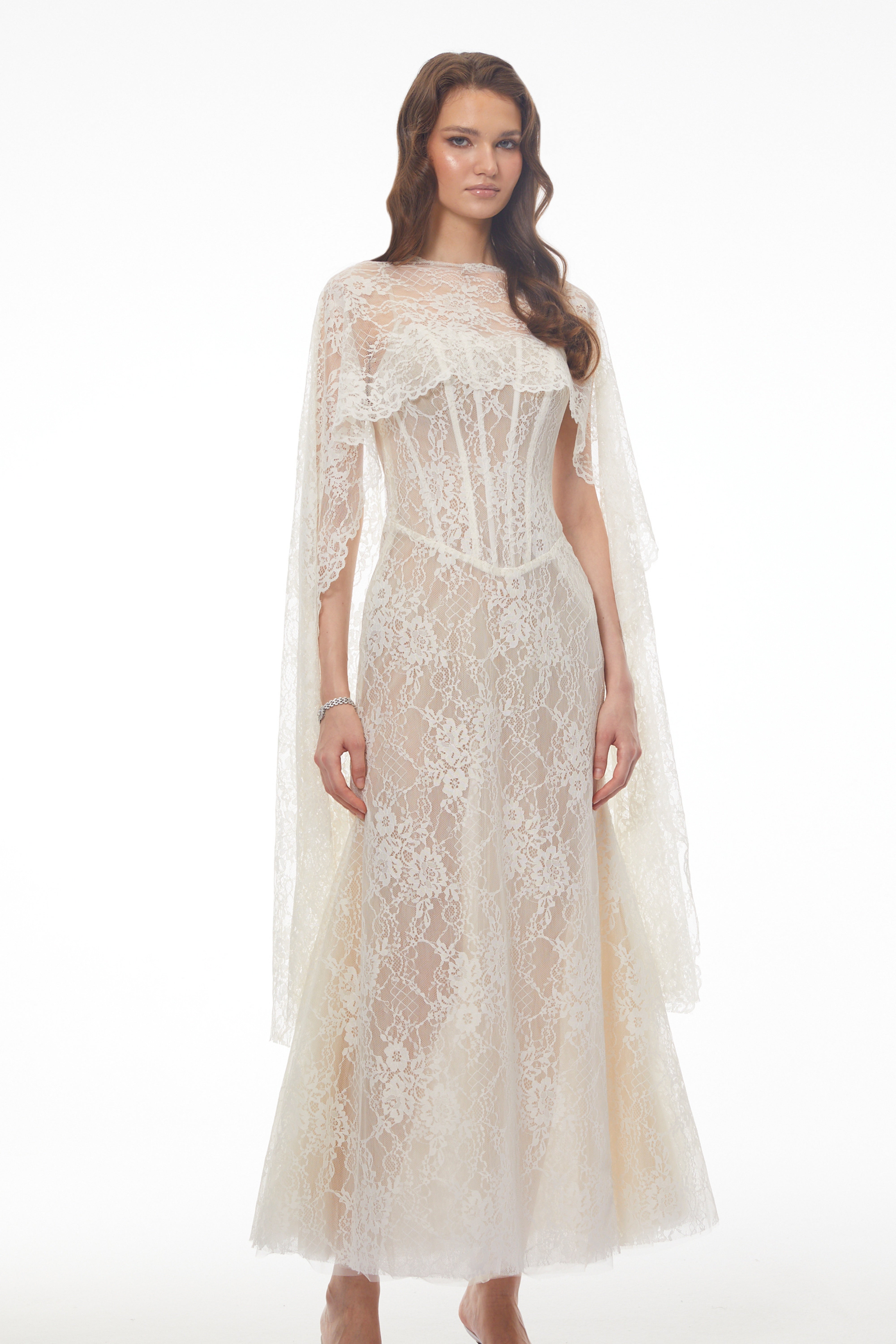 White lace maxi dress with a corset bodice, high neckline, and long draped cape sleeves
