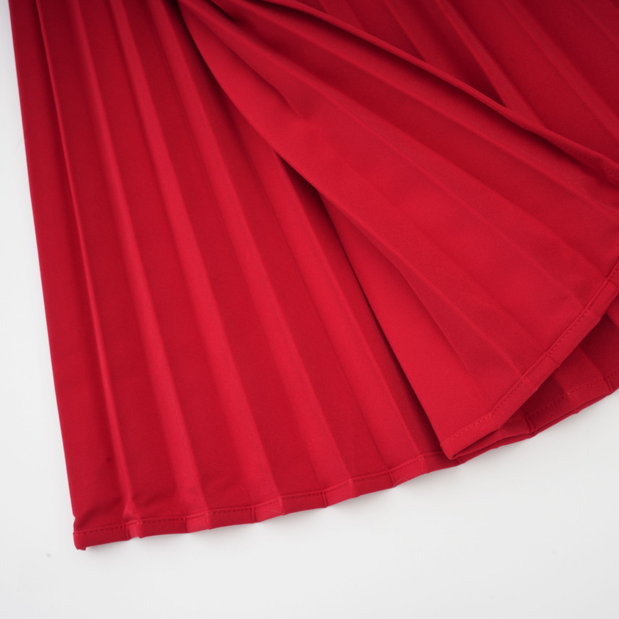 Robe rouge à manches longues et épaules dénudées, avec un panneau plissé sur la jupe