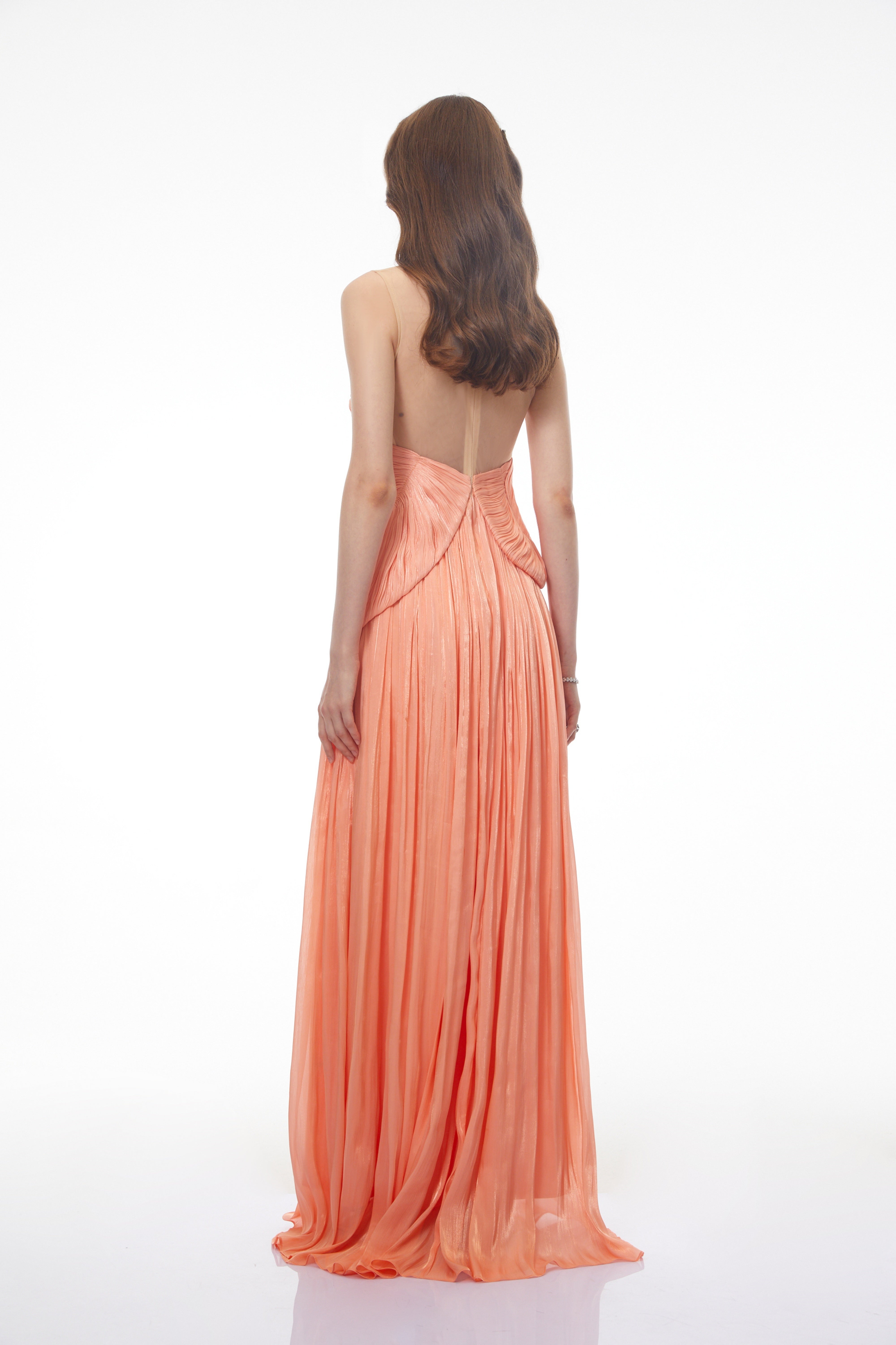 Peach pleated gown with a structured bodice and sheer illusion neckline