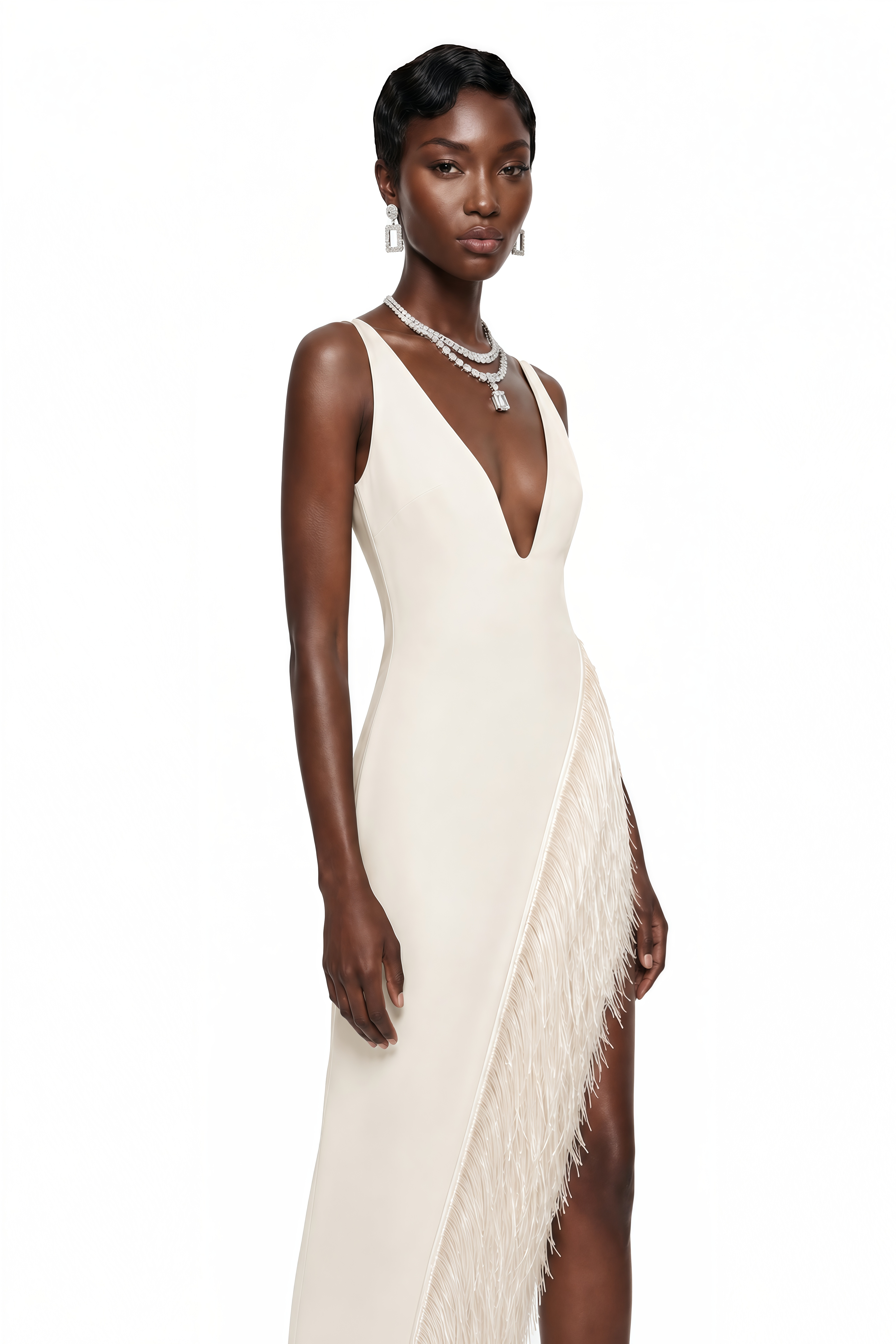 White maxi dress with a plunging V-neckline and a high slit trimmed with fringe