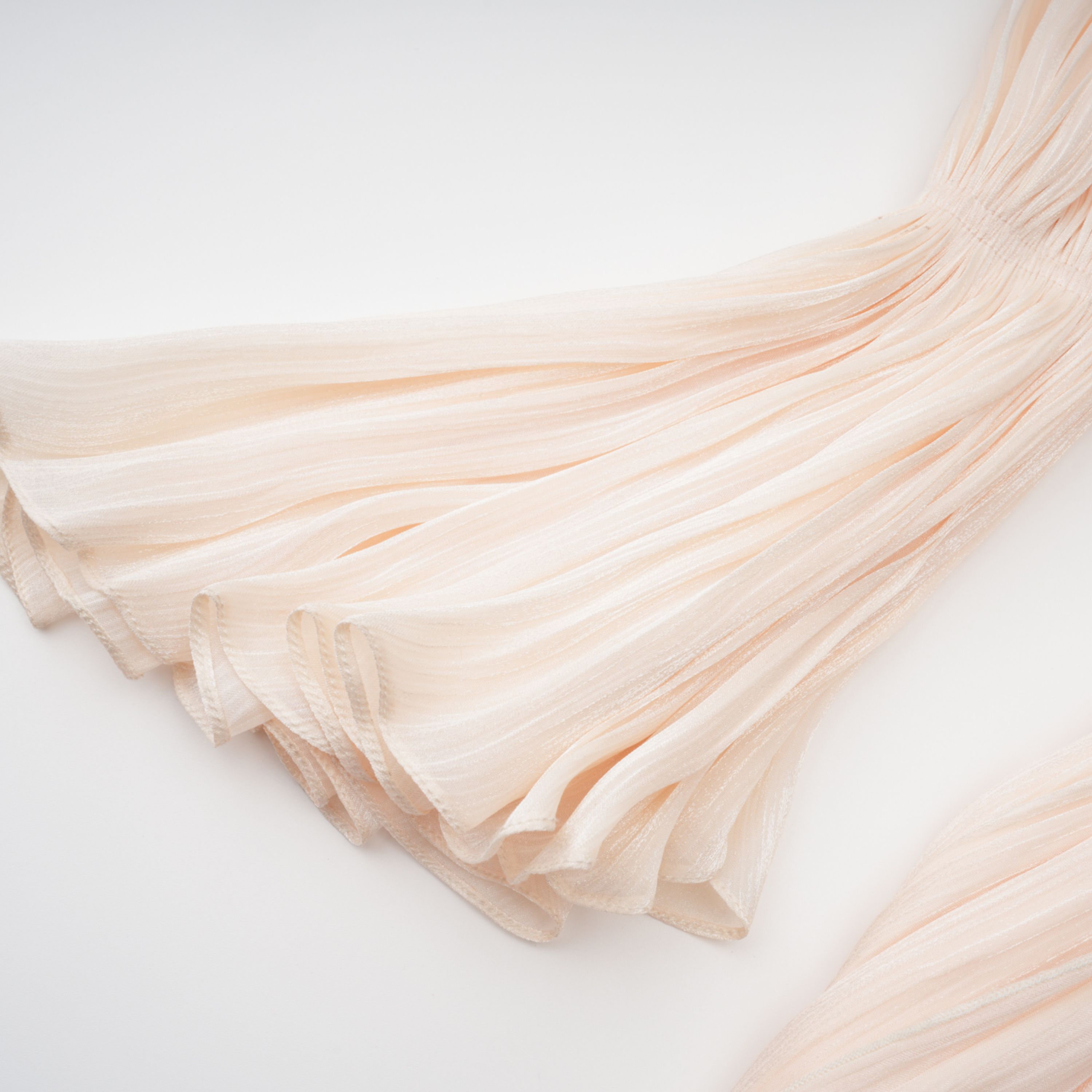 Cream plissé mini dress with a square neckline, structured puff sleeves, and a draped ruffled skirt