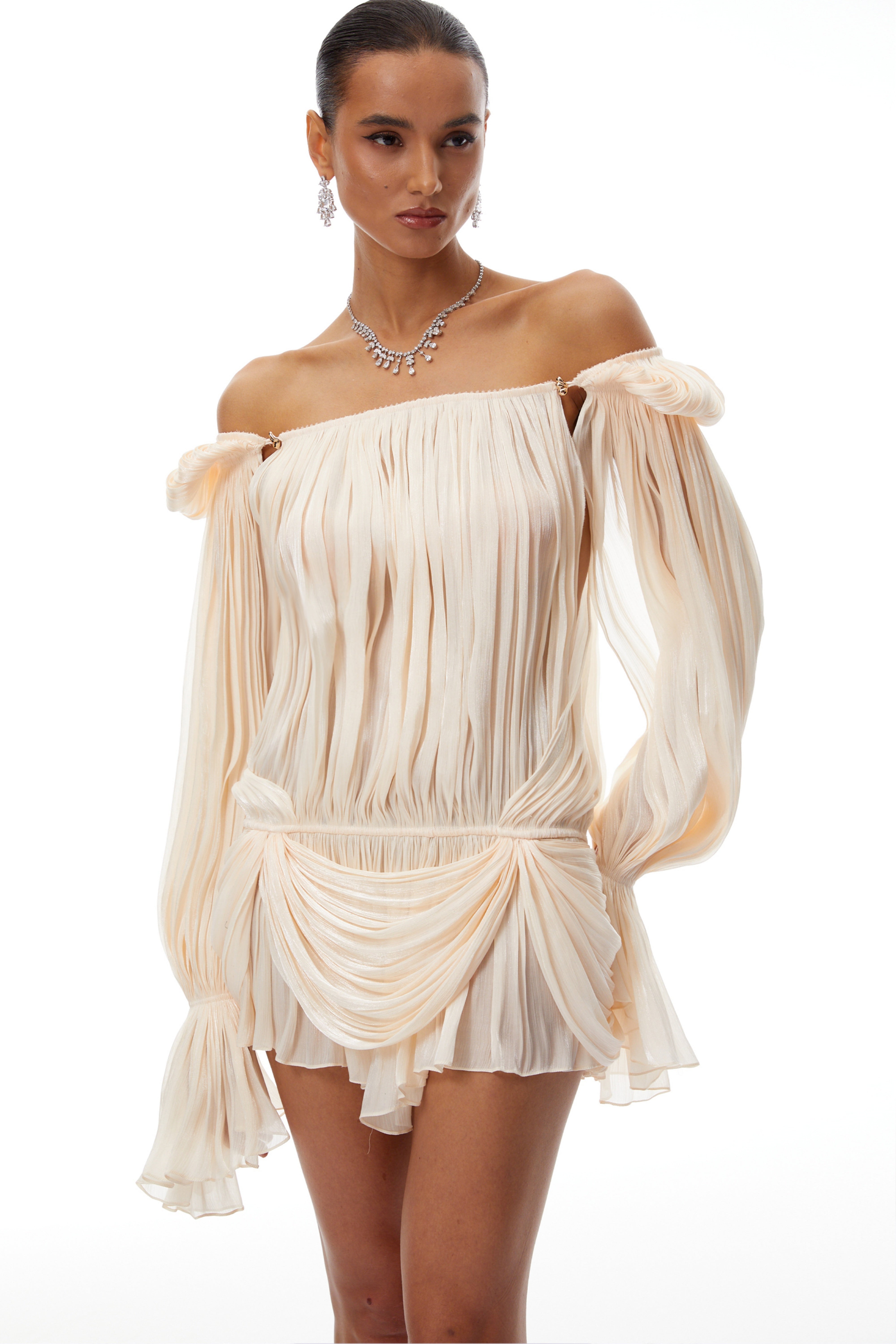 Cream plissé mini dress with a square neckline, structured puff sleeves, and a draped ruffled skirt