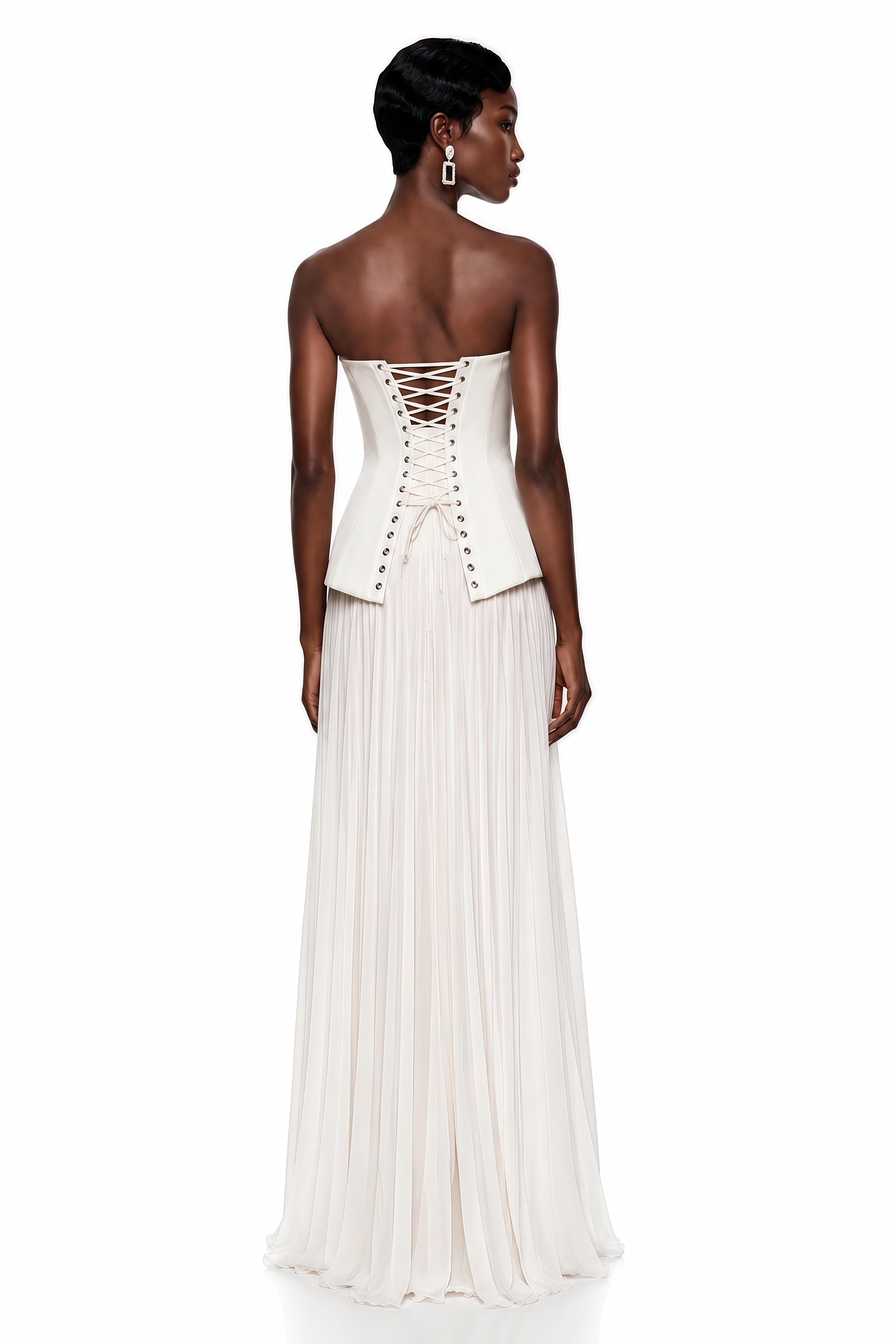 White strapless maxi dress with a structured peplum corset bodice, pleated skirt, and lace-underlaid high leg slit