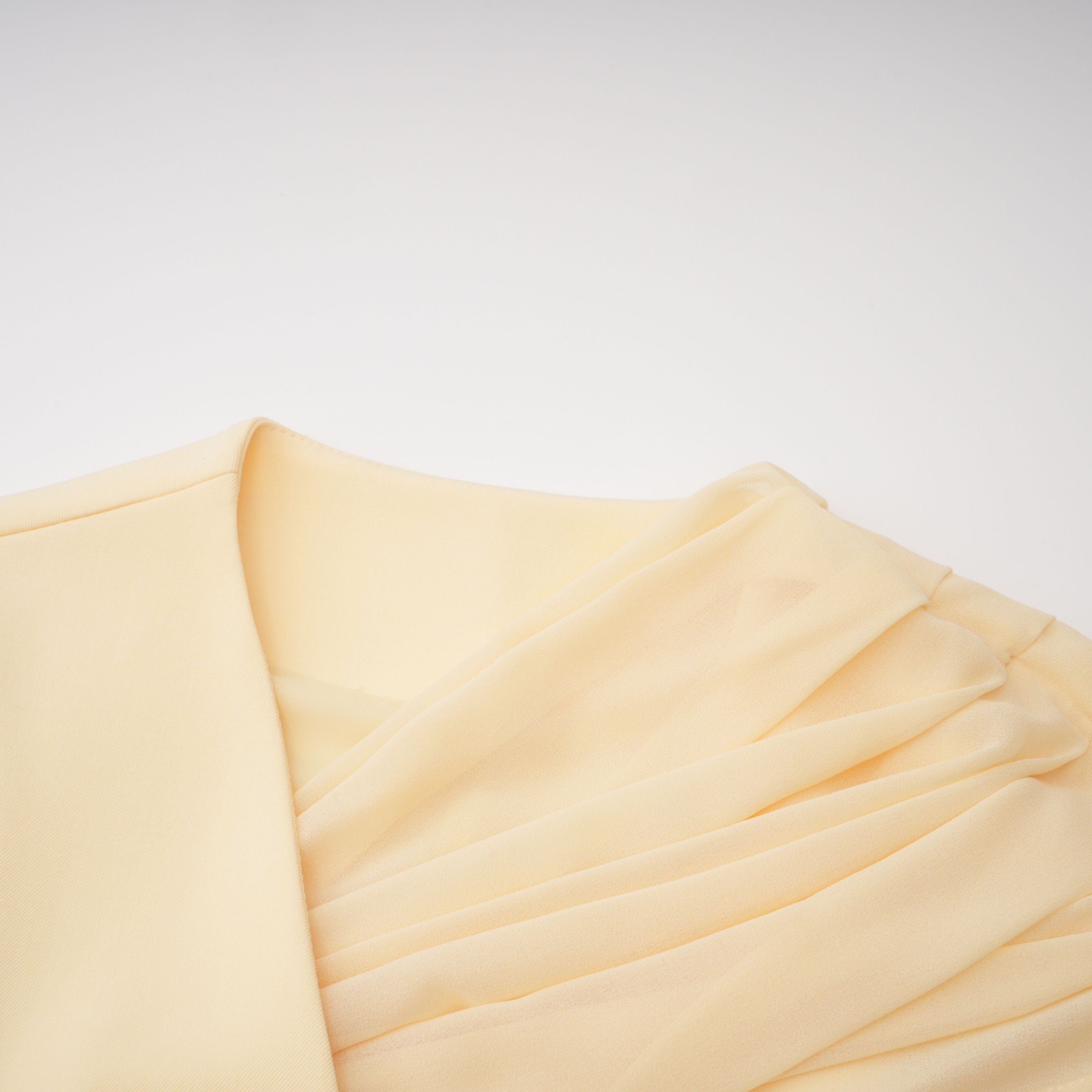 Pale yellow top and trousers set with an asymmetric blazer bodice, draped sheer neckline, and cape panels