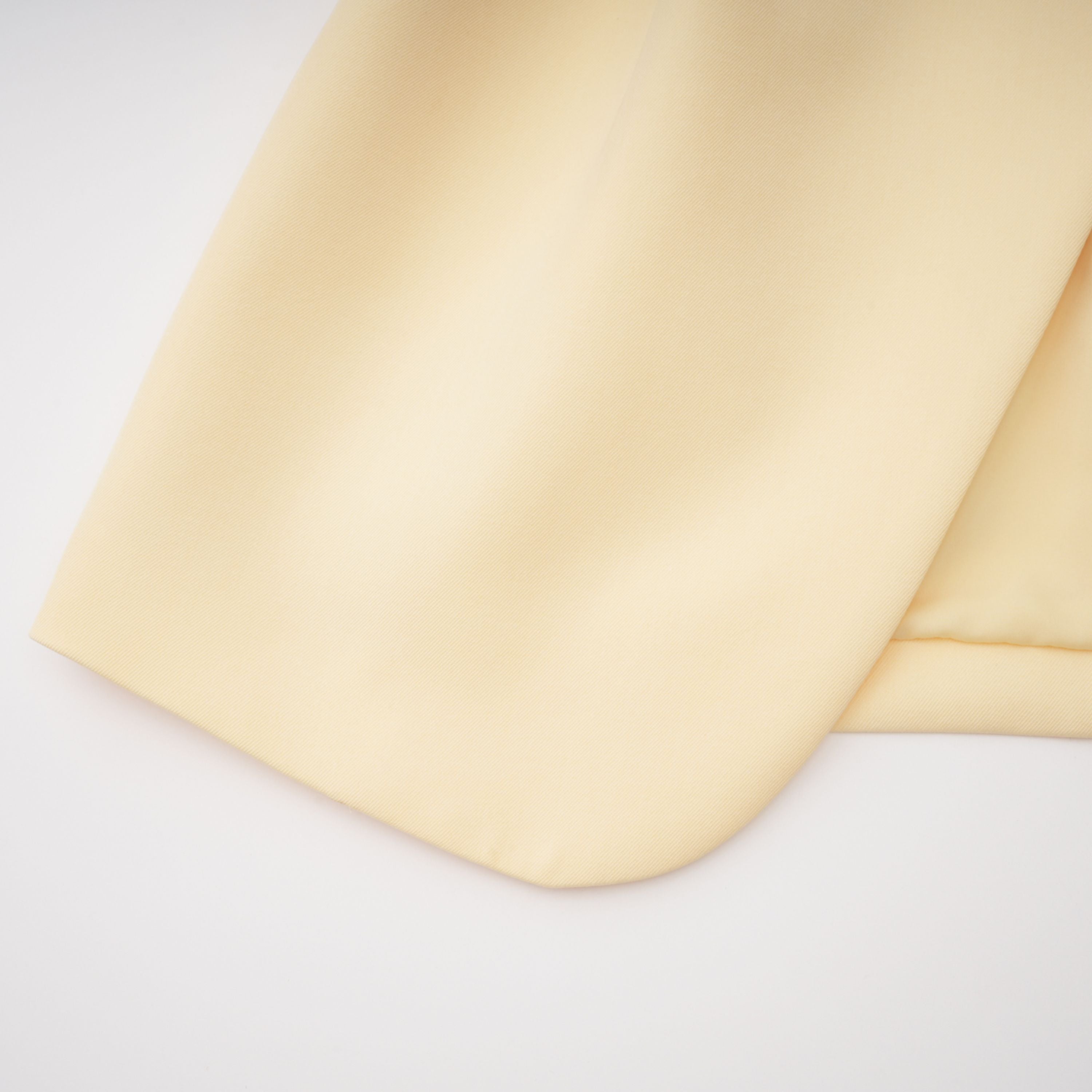 Pale yellow top and trousers set with an asymmetric blazer bodice, draped sheer neckline, and cape panels