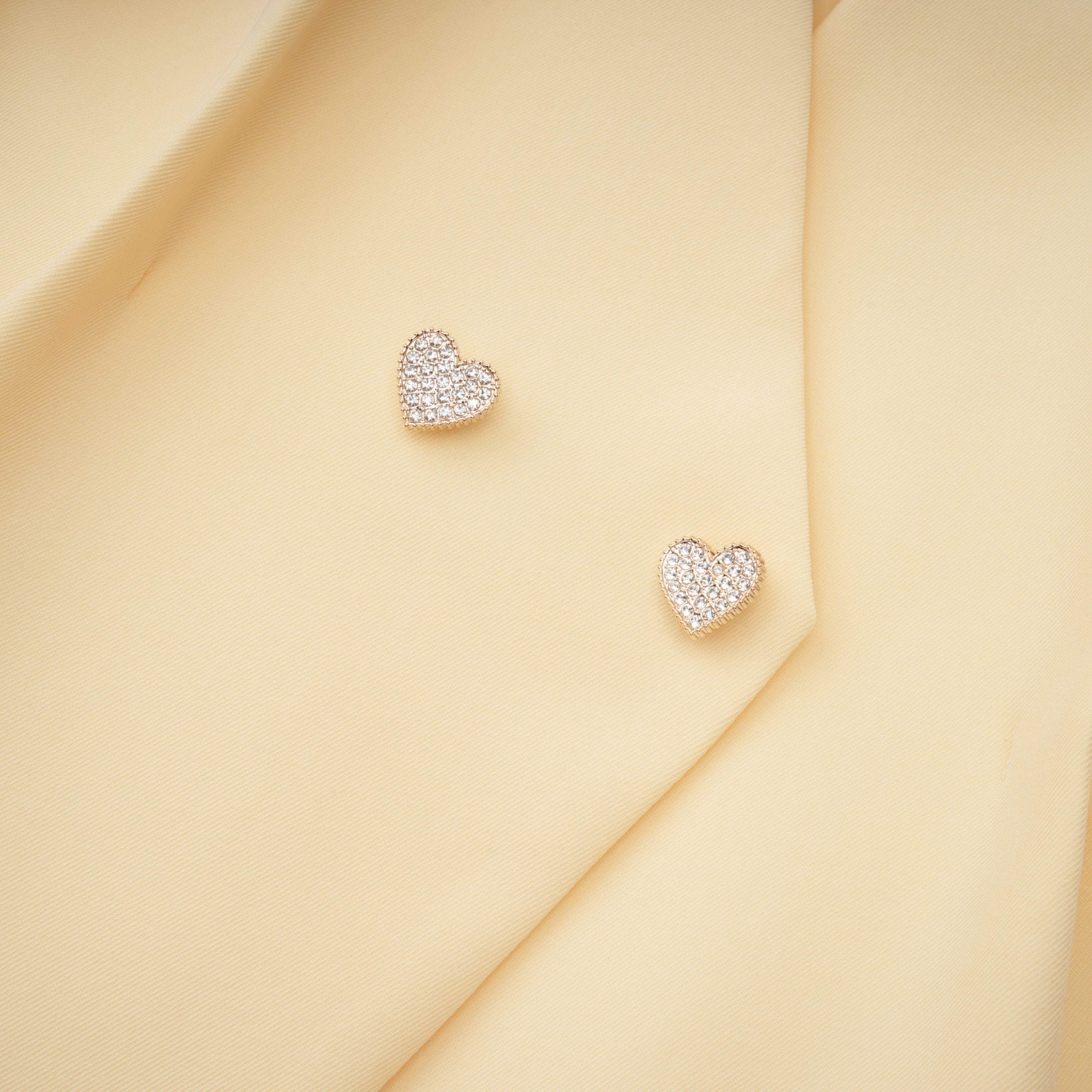 Pale yellow top and trousers set with an asymmetric blazer bodice, draped sheer neckline, and cape panels