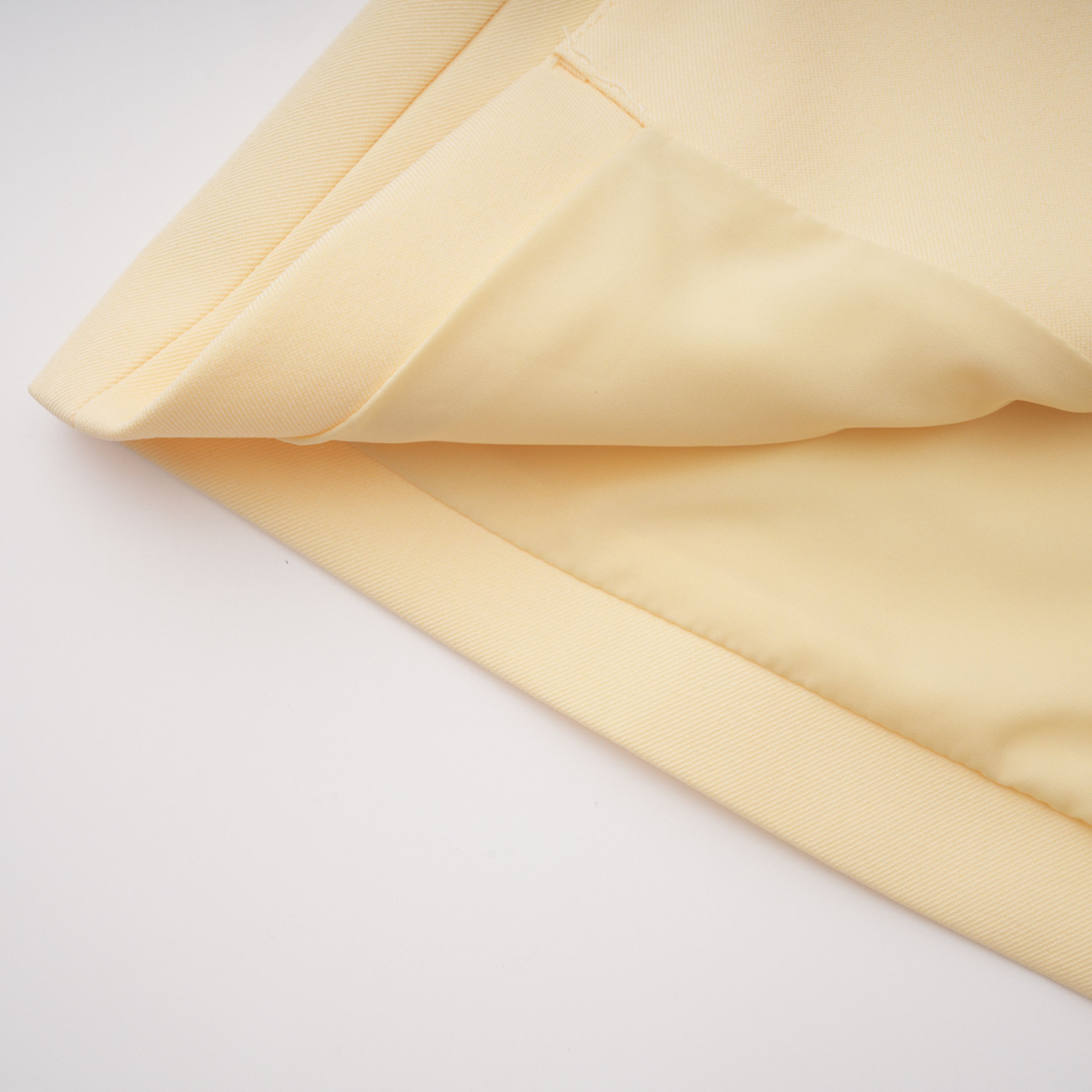 Pale yellow top and trousers set with an asymmetric blazer bodice, draped sheer neckline, and cape panels