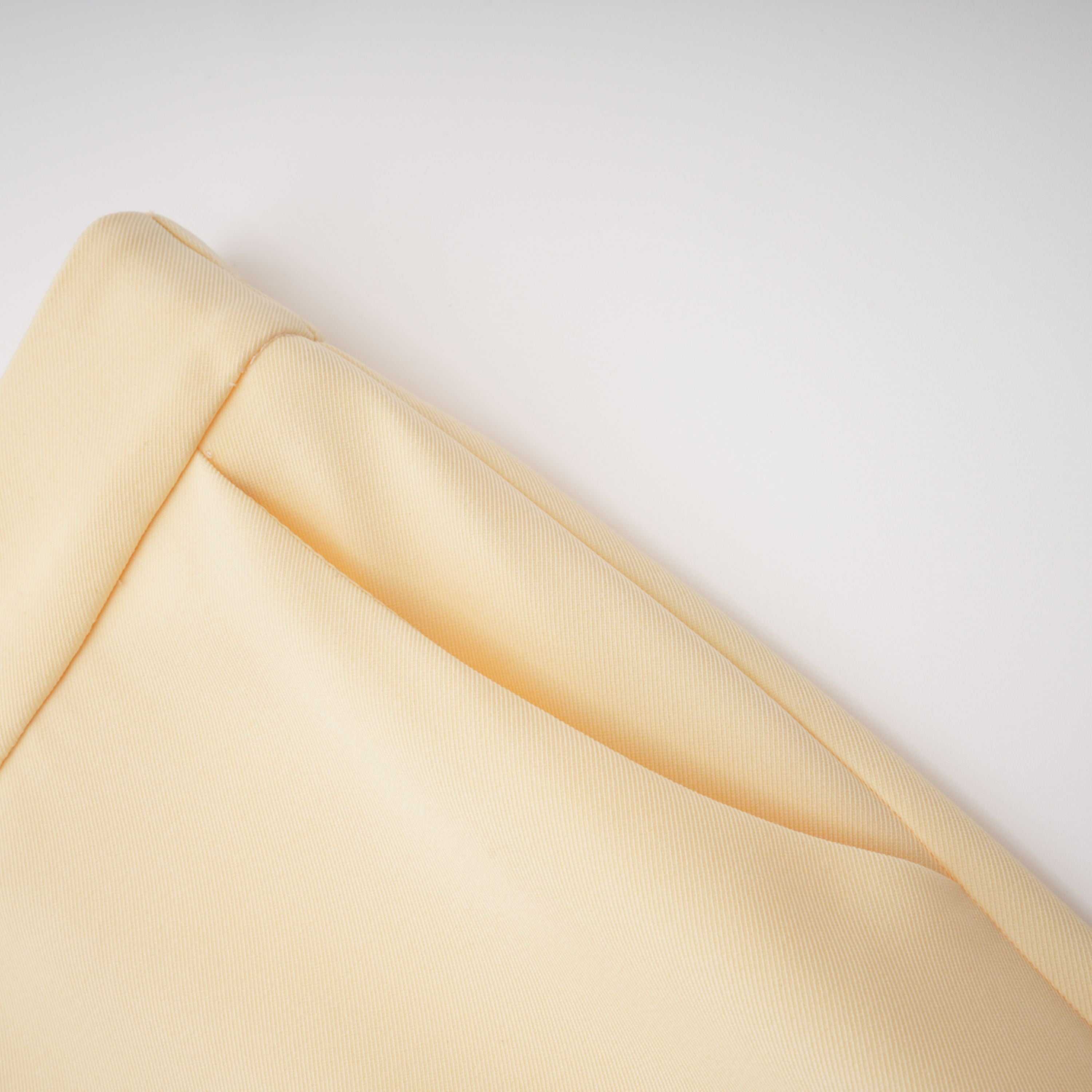 Pale yellow top and trousers set with an asymmetric blazer bodice, draped sheer neckline, and cape panels