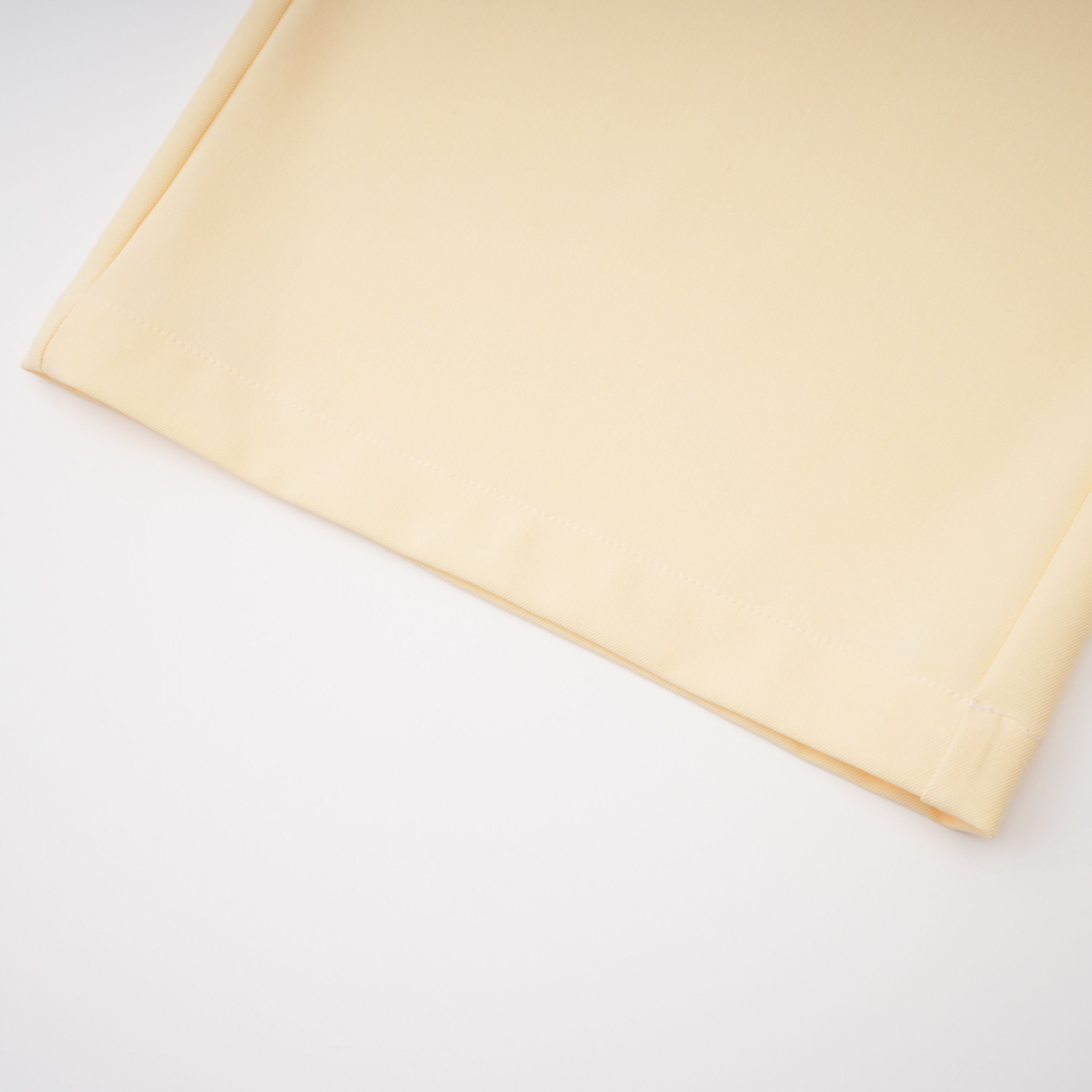 Pale yellow top and trousers set with an asymmetric blazer bodice, draped sheer neckline, and cape panels