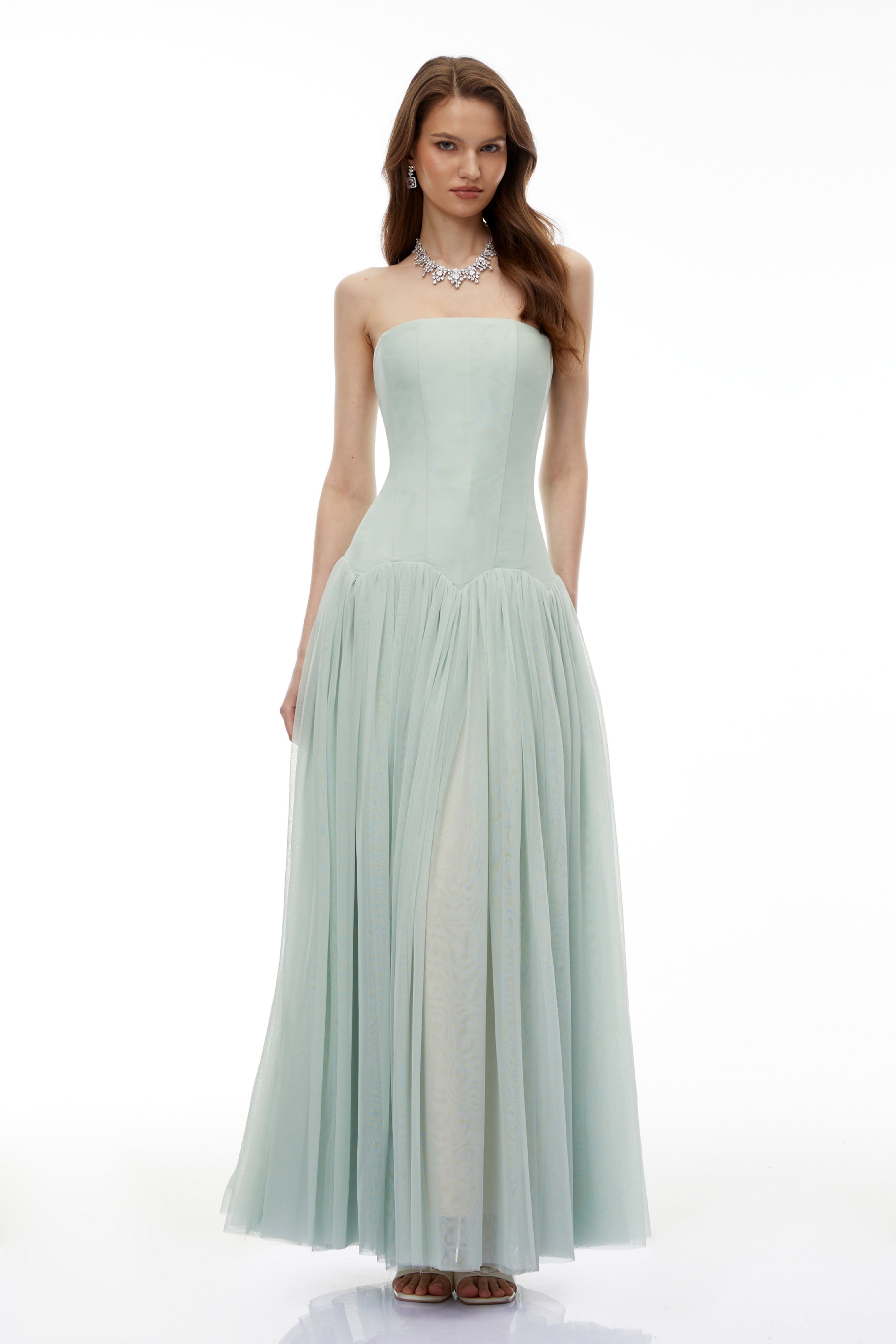 فستان أخضر فاتح بدون أكمام، يتميز بجزء علوي على طراز الكورسيه وتنورة منسدلة مطوية