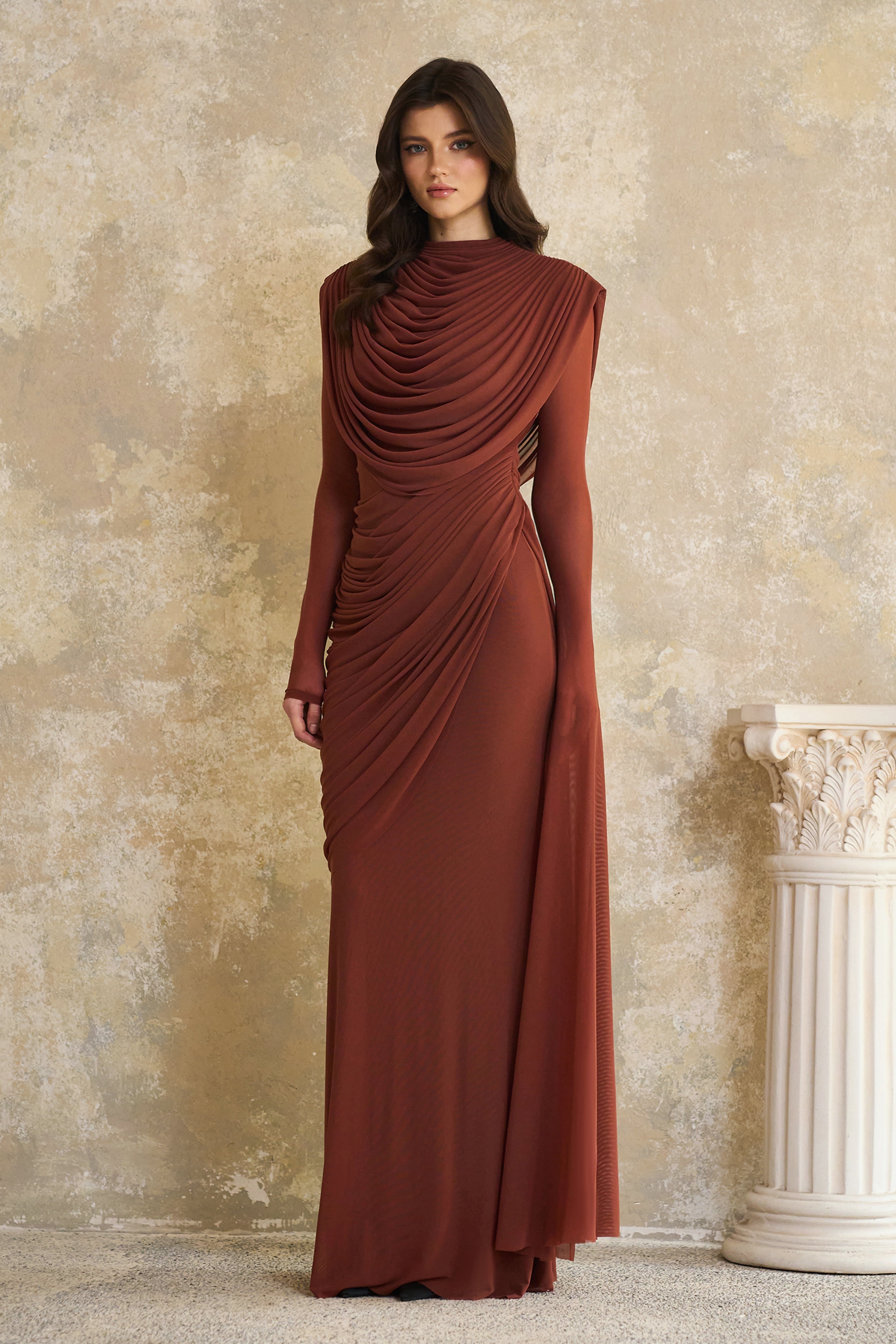 Rust-colored long-sleeve maxi dress with a draped cowl neckline and pleated bodice