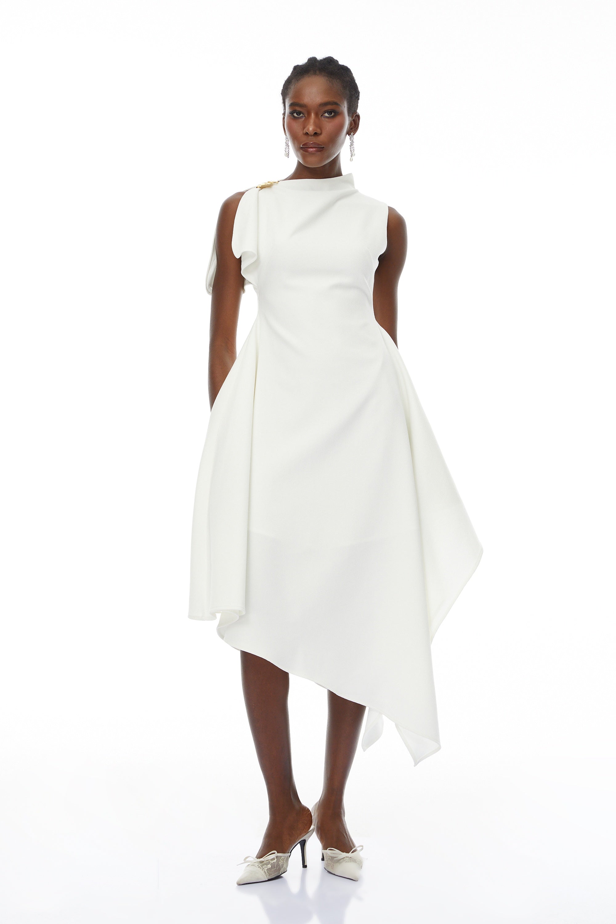 White sleeveless midi dress featuring a high drape neck with a brooch detail and a structured asymmetric handkerchief skirt