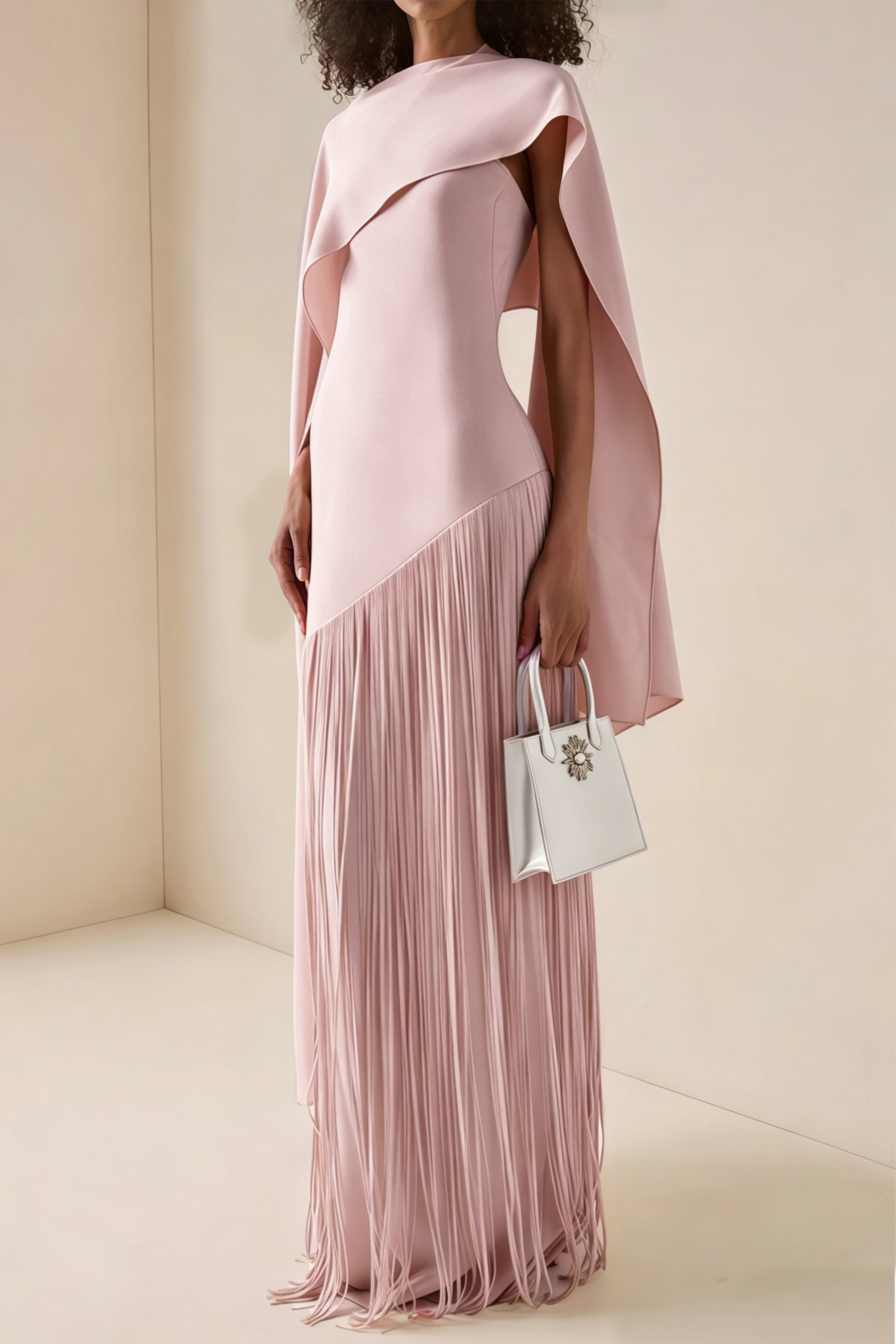 Light pink cape maxi dress with an asymmetrical waist and long fringe skirt