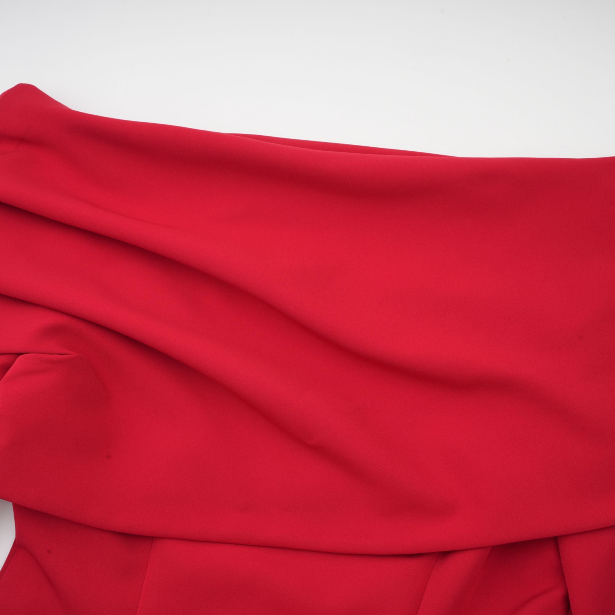 Robe rouge à manches longues et épaules dénudées, avec un panneau plissé sur la jupe