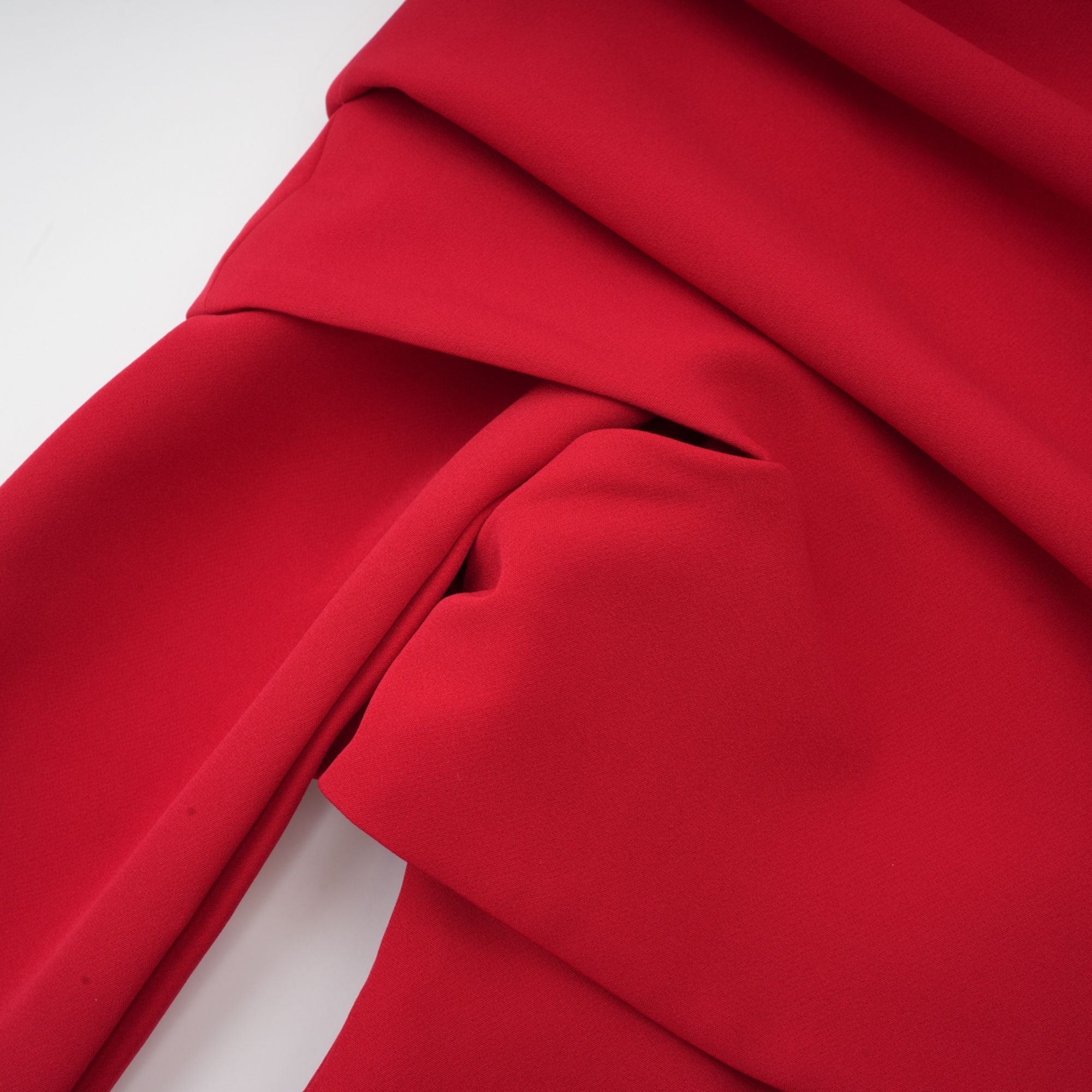 Robe rouge à manches longues et épaules dénudées, avec un panneau plissé sur la jupe