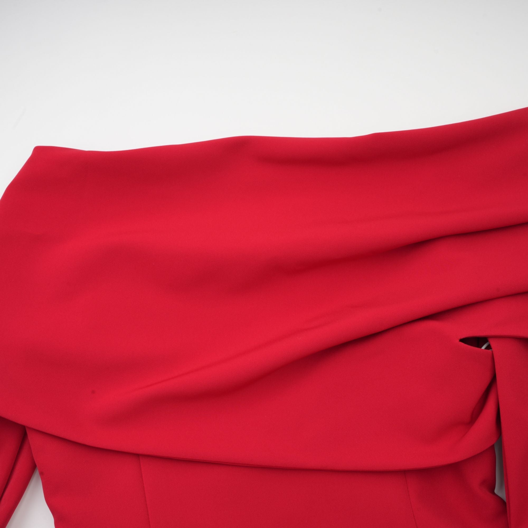 Robe rouge à manches longues et épaules dénudées, avec un panneau plissé sur la jupe