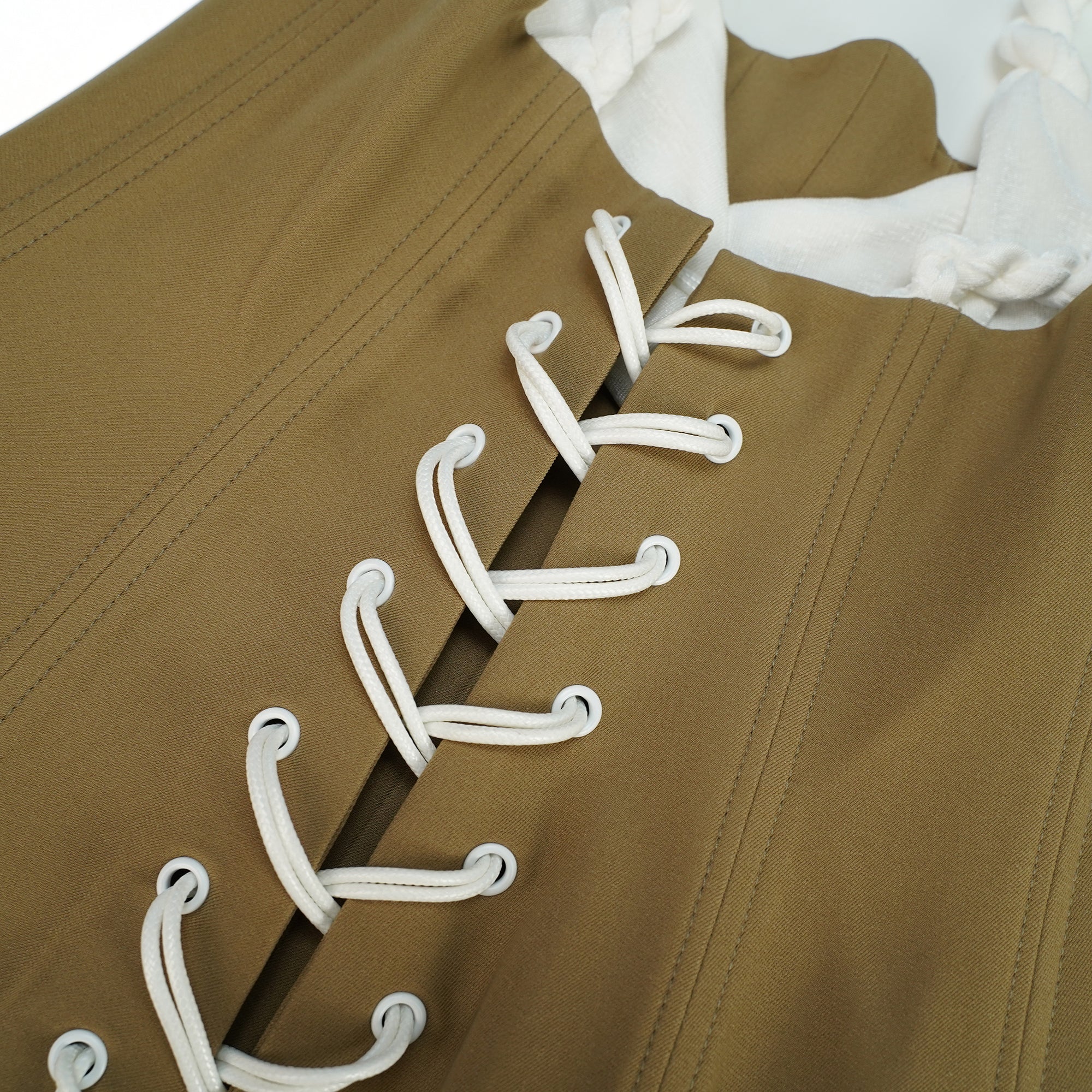 Mini-robe caraco blanche, avec un corsage structuré couleur beige et une jupe drapée à volants, agrémentée de cordons de serrage