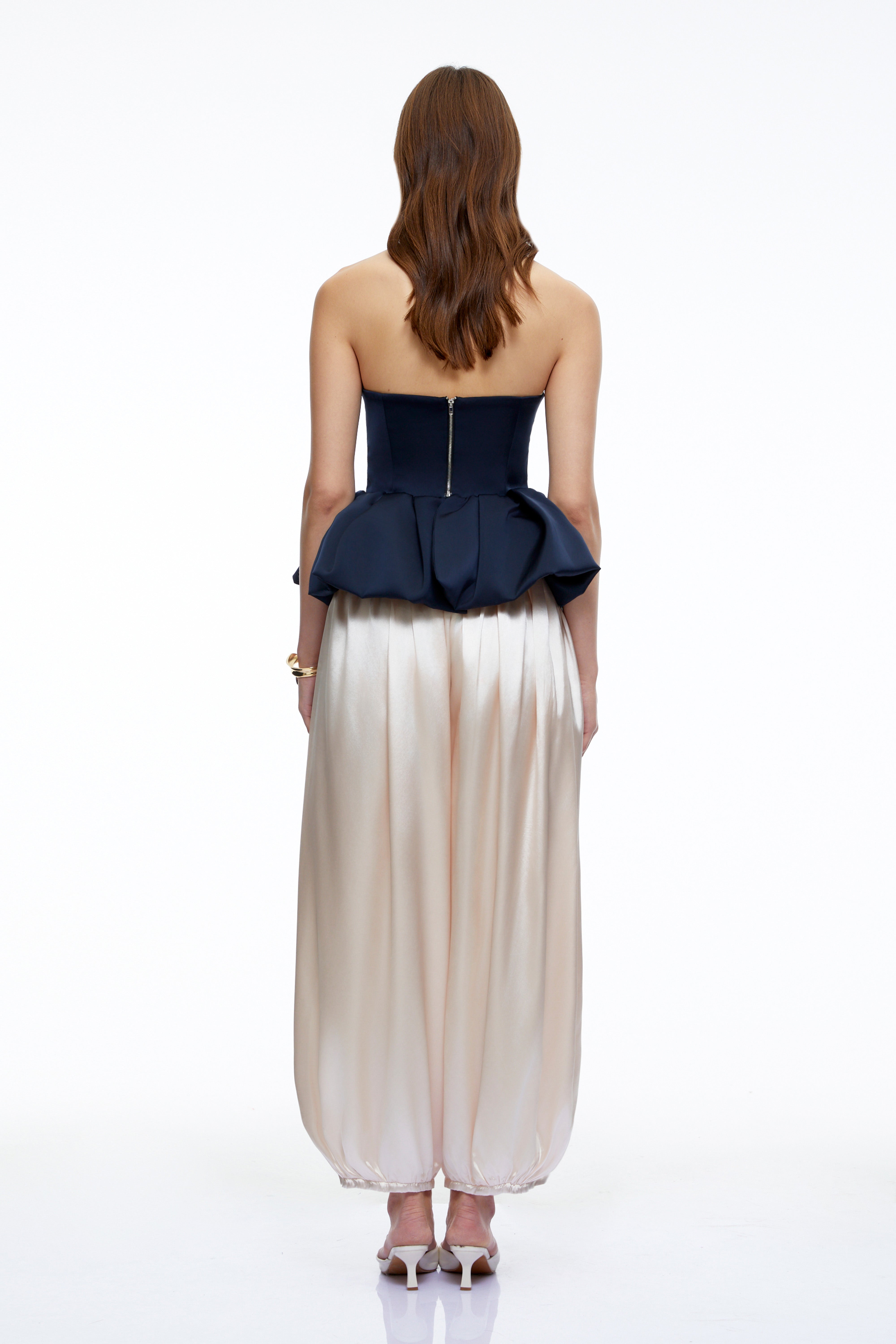 Ensemble composé d'un bustier bleu marine sans bretelles à basque et d'un pantalon bouffant beige